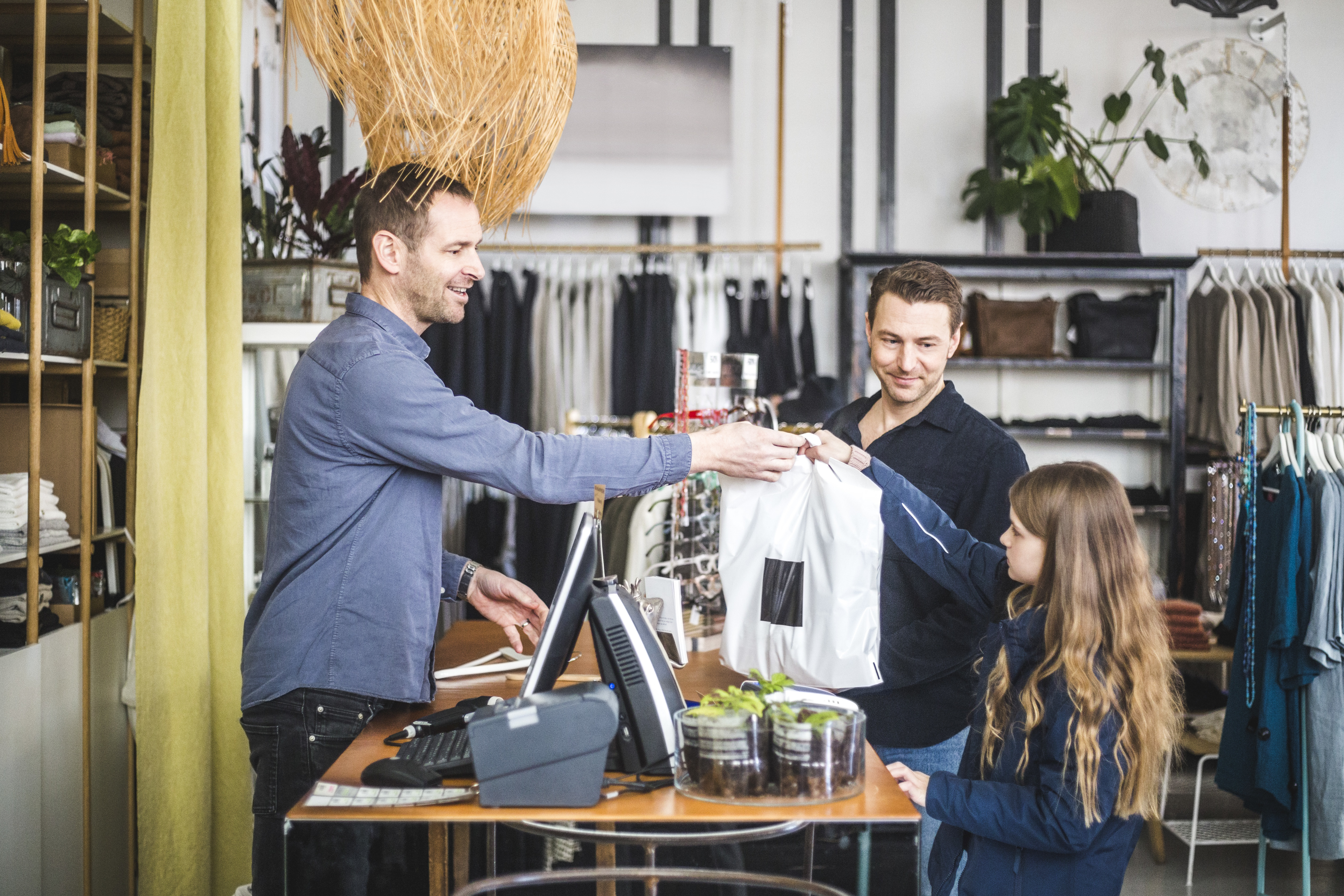 Flicka får en påse med varor i kassan i en butik