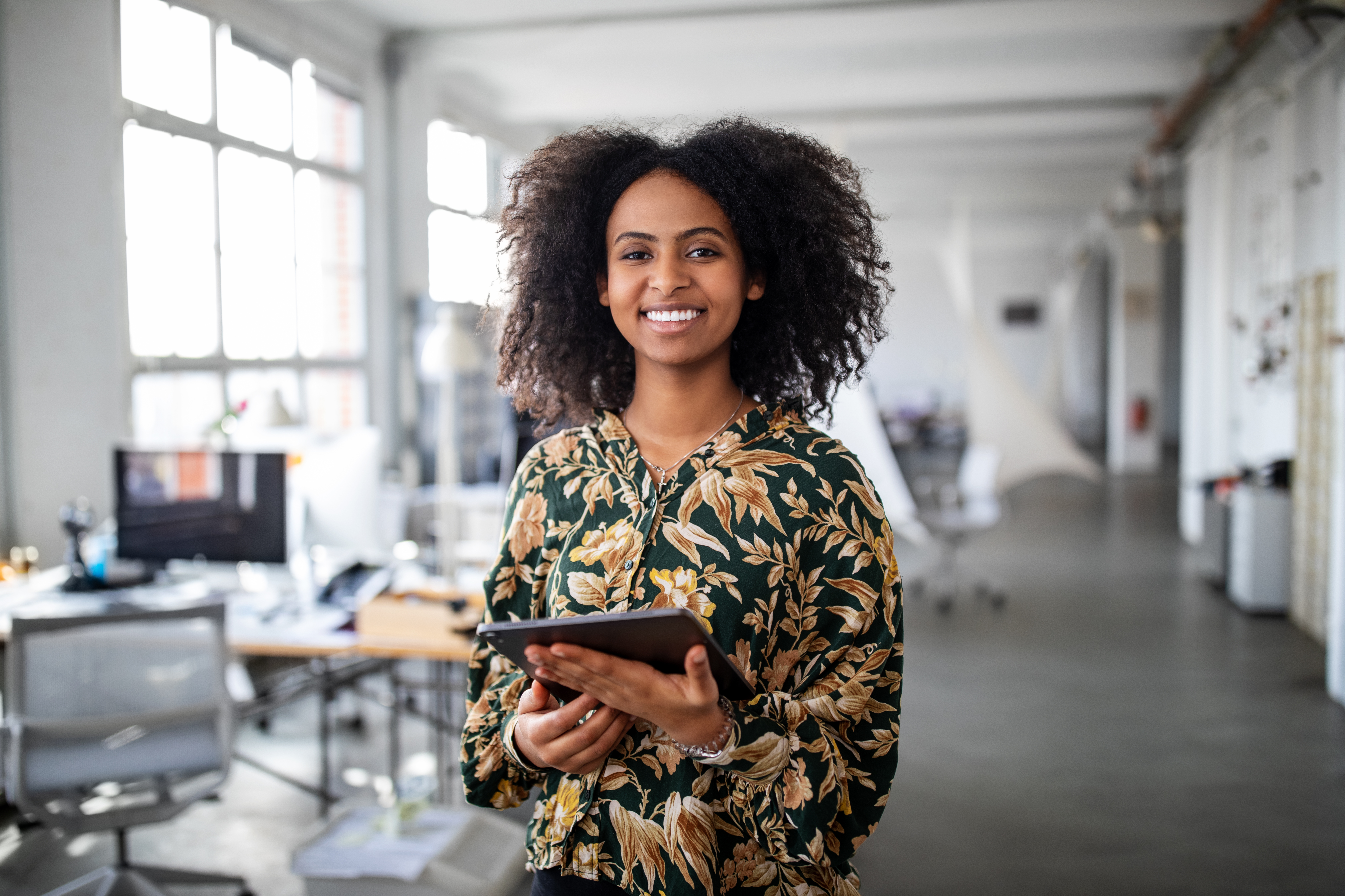 Smiling woman standing with digital tablet in office