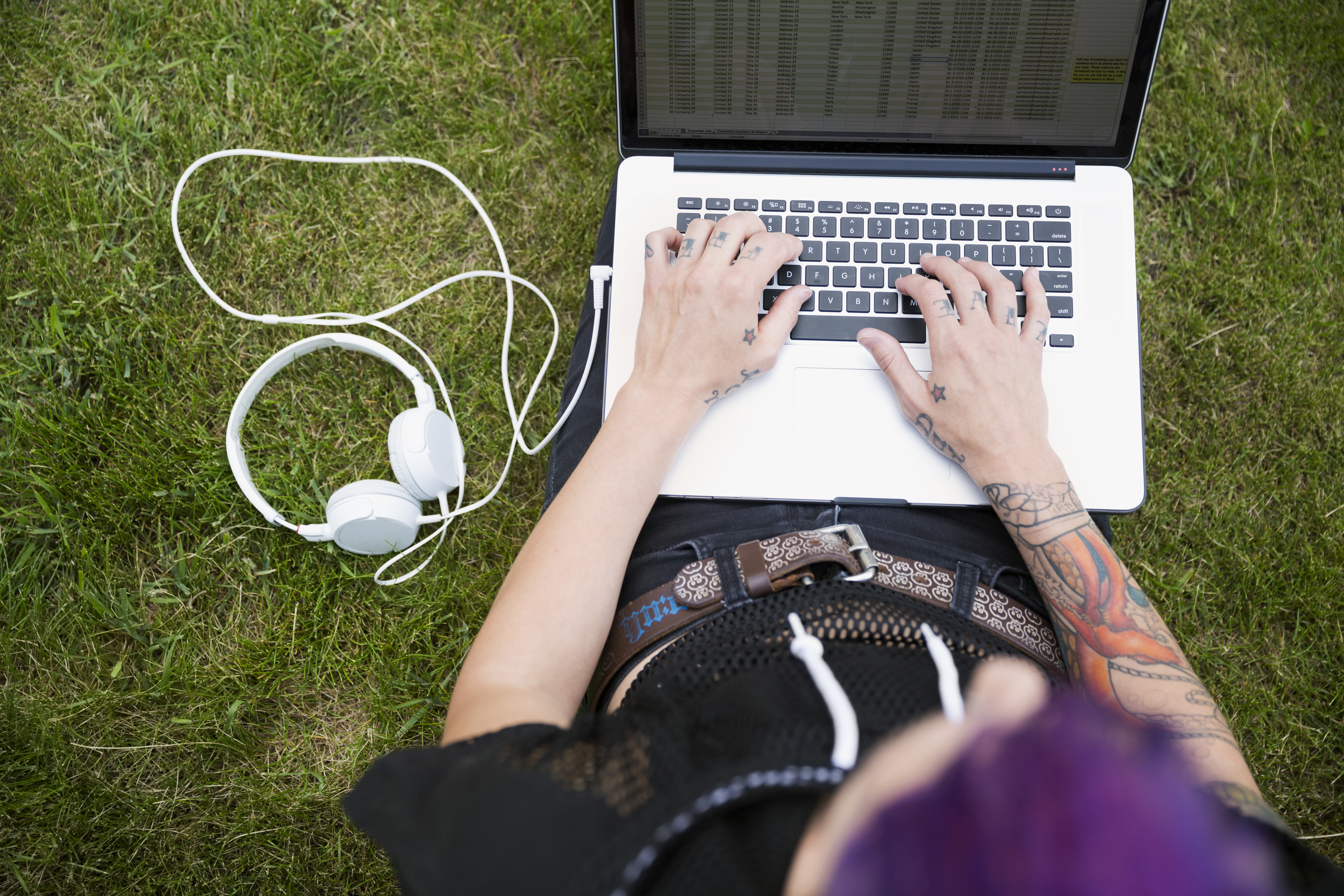 Young woman sitting in the grass with laptop in her knee