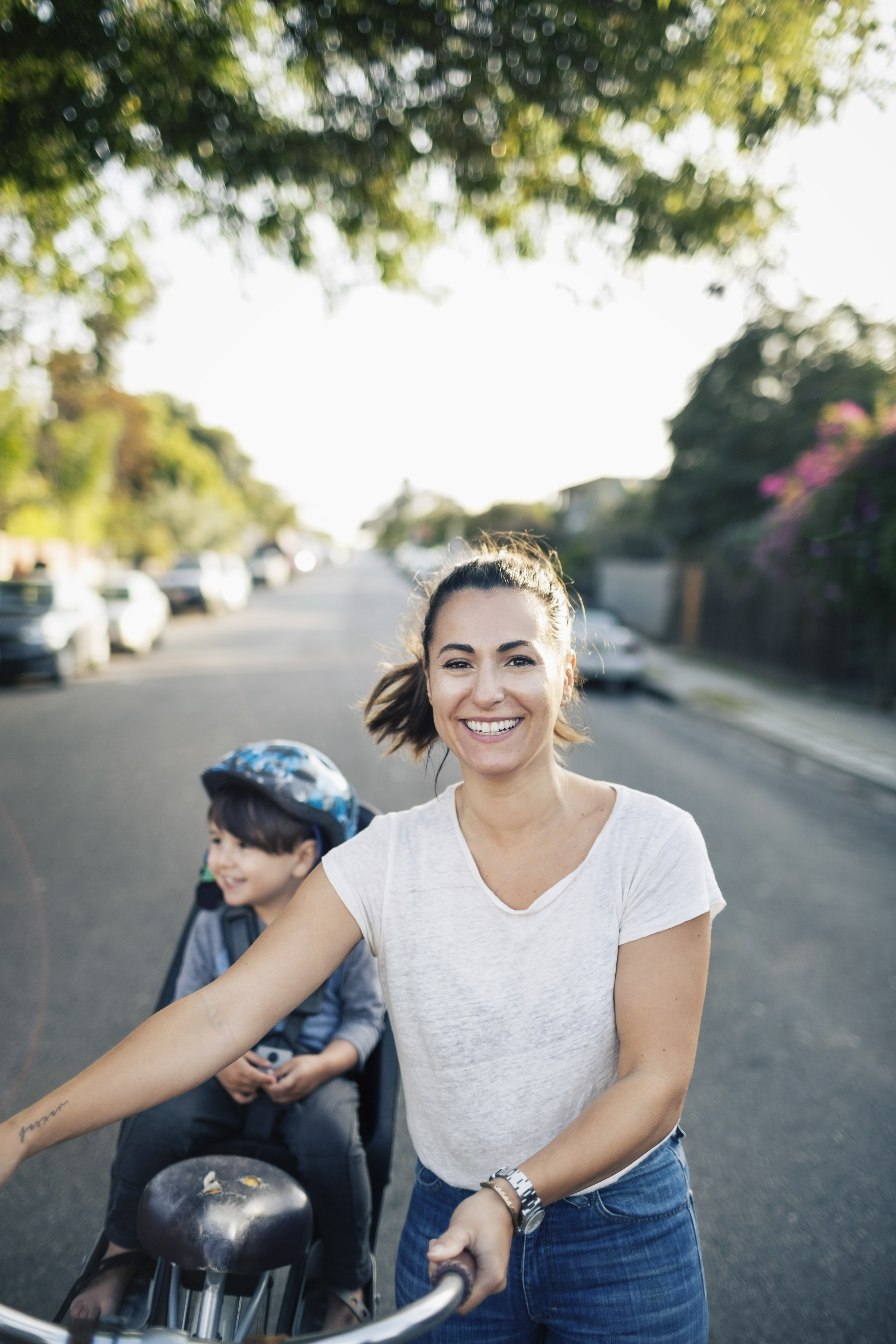 Confident - woman leading bicycle with child in bicycle seat